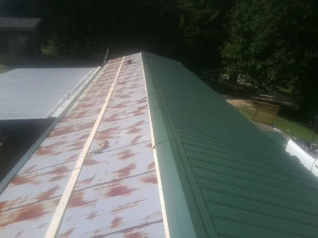 Old rusted panels beside newly installed green metal roofing — Wind Damage Roof Repair by Roofing Brothers in Lynchburg