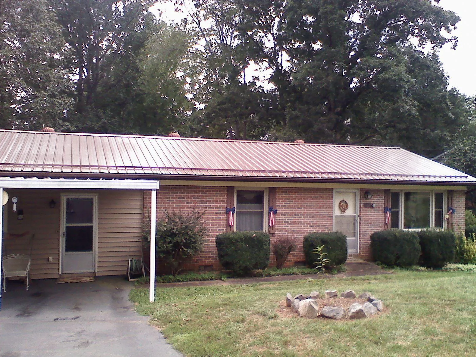 Bronze metal roof and carport on a brick ranch home — Roof Repair work by our crew in Lynchburg