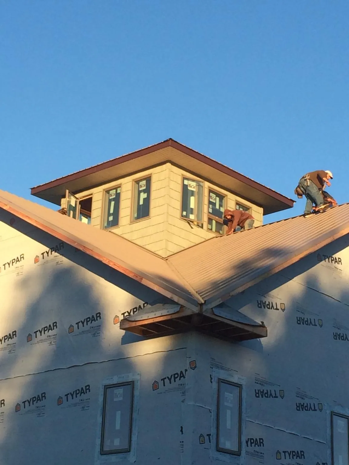 Roofers working around a rooftop cupola on a new metal roof at sunset — Roof Waterproofing in Lynchburg by Roofing Brothers